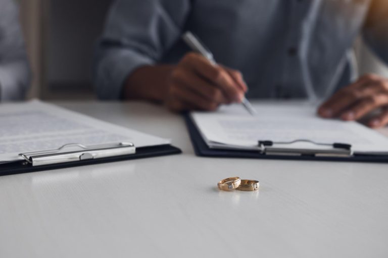 Firma de documentos de divorcio con anillos de casamiento sobre la mesa