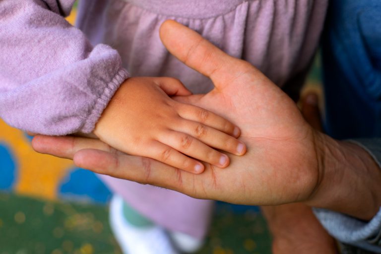 Mano de un adulto sosteniendo la de un niño – adopción